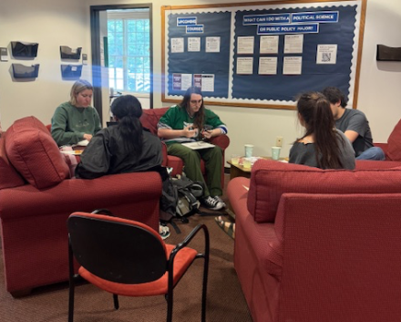 Students sitting in a circle in red chairs to celebrate the work of two-term editorship of their national undergraduate research journal.
